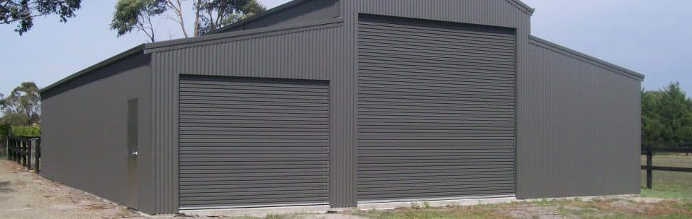 An American barn in grey, featuring an open garage door that reveals its expansive interior space.